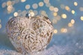 Glass heart on a snow and toned blurred color background of glittering bokeh with glowing lights. Christmas decoration. Copy space Royalty Free Stock Photo