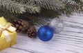 Christmas decoration with golden gift box blue and silver balls natural fir branches cones on white wooden background Royalty Free Stock Photo