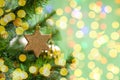 Christmas decoration golden twinkling star on a branch of a christmas tree, christmas tree toy, sparkling shiny background copy