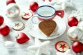 Christmas decoration with milk plate with gingerbread snowflakes and baubles on a white table.