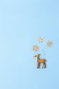 Christmas decoration, naturalistic toy roe deer and three little wooden snowflakes on pastel blue background, copy space. Festive Royalty Free Stock Photo