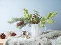 Christmas decoration with pine tree branches in vase and ornaments on wooden table over bright background Royalty Free Stock Photo