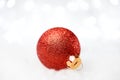 Christmas Decoration with Red Ball in the Snow on the Blurred Background with Holiday Lights. Greeting Card Royalty Free Stock Photo