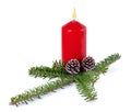 Christmas decoration - red burning candle, spruce branch and cones isolated on white background with shadow reflection. Royalty Free Stock Photo