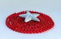 Christmas decoration: silver star and circle folded red beaded garland on white background. Concept of Christmas and New Year deco Royalty Free Stock Photo