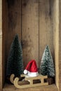 Christmas decoration sledge with Santa Claus hat and trees in a