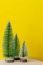 Christmas decoration three fir trees in front of a yellow background