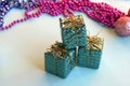 Christmas decoration for the Christmas tree in the form of small shiny gifts on a blue background. Royalty Free Stock Photo