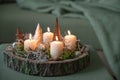 Christmas decoration and white advent candles and on a rustic tree tray on an gray green ottoman by a couch with a blanket, cozy