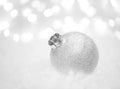 Christmas Decoration with White Ball in the Snow on the Blurred Background with Lights. Greeting Card Royalty Free Stock Photo