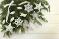 Christmas decoration - white crocheted stars, snowflakes and silver cones on green spruce branches on white wooden background. Royalty Free Stock Photo