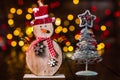 Christmas decorations against blurred background and out of focus lights. Decorative wooden snowman and glittery Christmas balls Royalty Free Stock Photo