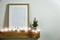 Christmas decorations in bright shiny colors with Christmas lights and frame picture. Wooden shelf and white wall background. Royalty Free Stock Photo