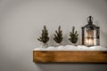 Christmas decorations in bright shiny colors with Christmas lights and lantern. Wooden shelf and white wall background.