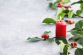 Christmas decorations, candle and holly leaves with red berries. Royalty Free Stock Photo