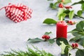 Christmas decorations, candle and holly leaves with red berries. Royalty Free Stock Photo