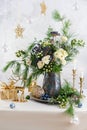 Christmas decorations, candles, gift boxes and flower bouquet. Winter arrangement with roses, fir branches, winter berries. Royalty Free Stock Photo