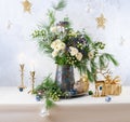 Christmas decorations, candles, gift boxes and flower bouquet. Winter arrangement with roses, fir branches, winter berries. Royalty Free Stock Photo