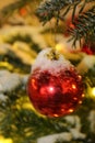 Christmas decorations on the Christmas tree in red and gold colors strewn with lights, close-up. Royalty Free Stock Photo