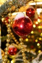 Christmas decorations on the Christmas tree in red and gold colors strewn with lights, close-up. Royalty Free Stock Photo