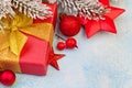 Christmas decorations closeup. Gift box with gold ribbon, red glass balls, fir branch and holly berries on blue frozen stucco Royalty Free Stock Photo