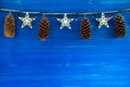 Christmas decorations with cones and Christmas lights on the blue wooden background. Royalty Free Stock Photo