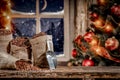 Christmas decorations and fresh coffee beans in jute sack with blurred christmas tree and sowy night window background.