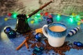 Christmas decorations garland cup of coffee with milk cinnamon sticks scattered coffee beans and black ceramic Cezve Royalty Free Stock Photo