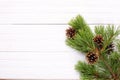 Christmas decorations, gilt cones on a pine branch on a white wooden background, copy space