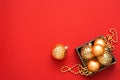 Christmas decorations. Gold baubles and beads in the wooden box on the red background with copy space. Royalty Free Stock Photo