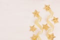 Christmas decorations, gold stars and curl ribbon on soft white wooden background. Royalty Free Stock Photo