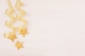 Christmas decorations, gold stars and curl ribbon on soft white wooden background. Royalty Free Stock Photo