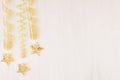 Christmas decorations, gold stars and curl ribbon on white wooden background. Royalty Free Stock Photo