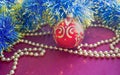 Christmas decorations, golden beads, blue tinsel and red ball with gold pattern, lie on a red background. Royalty Free Stock Photo