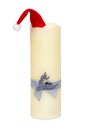 Christmas decorations isolated. Closeup of a large white candle with a light blue ribbon bow and a Santa Claus hat on top of it Royalty Free Stock Photo