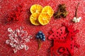 Christmas decorations lying neatly on a red background with sequins. Tangerines, wooden toys, a sprig of fir, anise stars Royalty Free Stock Photo