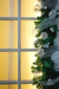 Christmas decorations made of spruce branches and white transparent balls and ribbons frame the window with wooden frame and yello Royalty Free Stock Photo