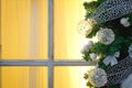 Christmas decorations made of spruce branches and white transparent balls and ribbons frame the window with wooden frame and yello Royalty Free Stock Photo