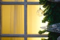 Christmas decorations made of spruce branches and white transparent balls and ribbons frame the window with wooden frame and yello Royalty Free Stock Photo