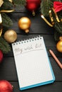 Christmas decorations and notebook with wish list on black wooden background. Planning concept Royalty Free Stock Photo