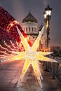 Christmas decorations on the Patriarch`s bridge on the background of the Cathedral of Christ the Savior in Moscow.