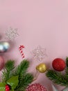 Christmas decorations, pine tree leaves, golden balls, snowflakes, red balls on pink background Royalty Free Stock Photo