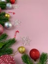 Christmas decorations, pine tree leaves, golden balls, snowflakes, red balls on pink background Royalty Free Stock Photo