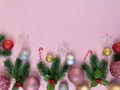 Christmas decorations, pine tree leaves, golden balls, snowflakes, red balls on pink background Royalty Free Stock Photo