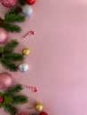 Christmas decorations, pine tree leaves, golden balls, snowflakes, red balls on pink background Royalty Free Stock Photo