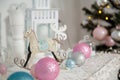 Christmas decorations, silver, blue and pink bulbs, white candles, wooden house and rocking horse toy Royalty Free Stock Photo