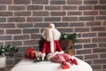 Christmas decorations, a toy Santa with a white beard sits against a brown brick wall. Royalty Free Stock Photo