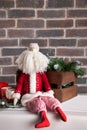 Christmas decorations, a toy Santa with a white beard sits against a brown brick wall. Royalty Free Stock Photo