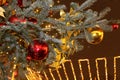 Christmas decorations on the Christmas tree in red and gold colors strewn with lights, close-up. Royalty Free Stock Photo