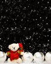 Christmas decorations view of teddy bear in red green sweater and Christmas hat and four silver evening balls with white snow on Royalty Free Stock Photo